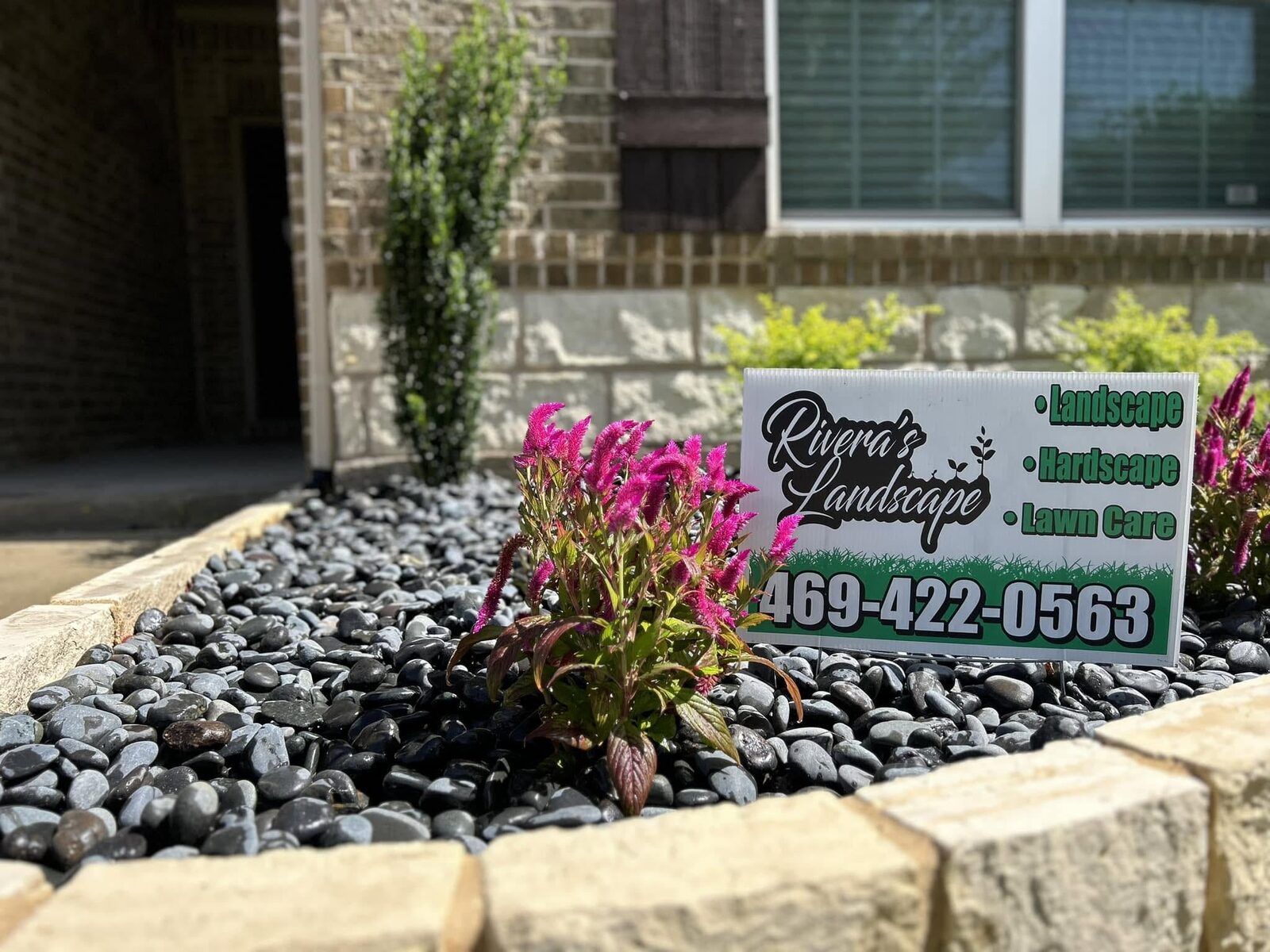 Stone-edged planter bed with river rock and fresh flowers.