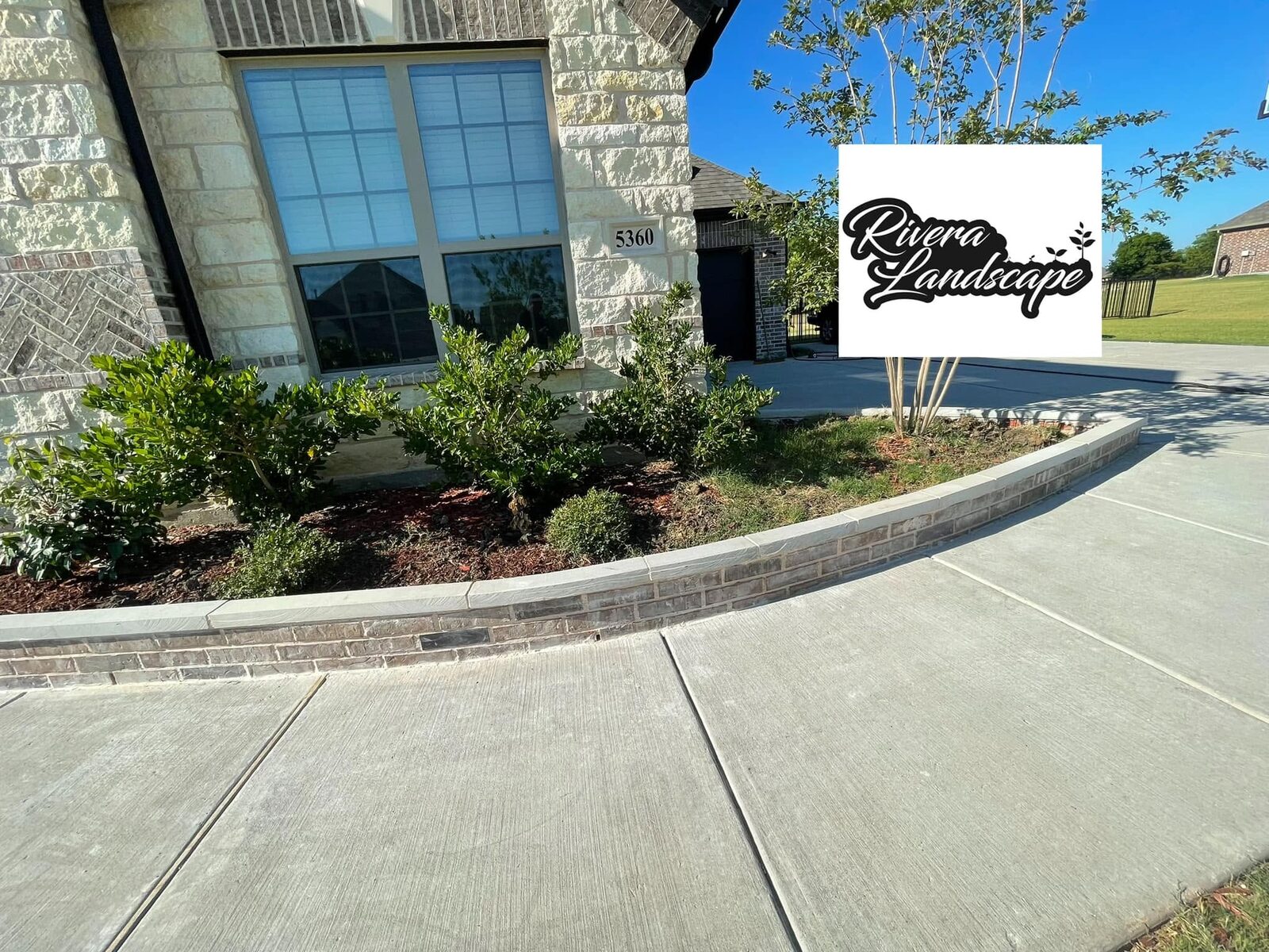 Stone-edged garden bed and plantings along a walkway.