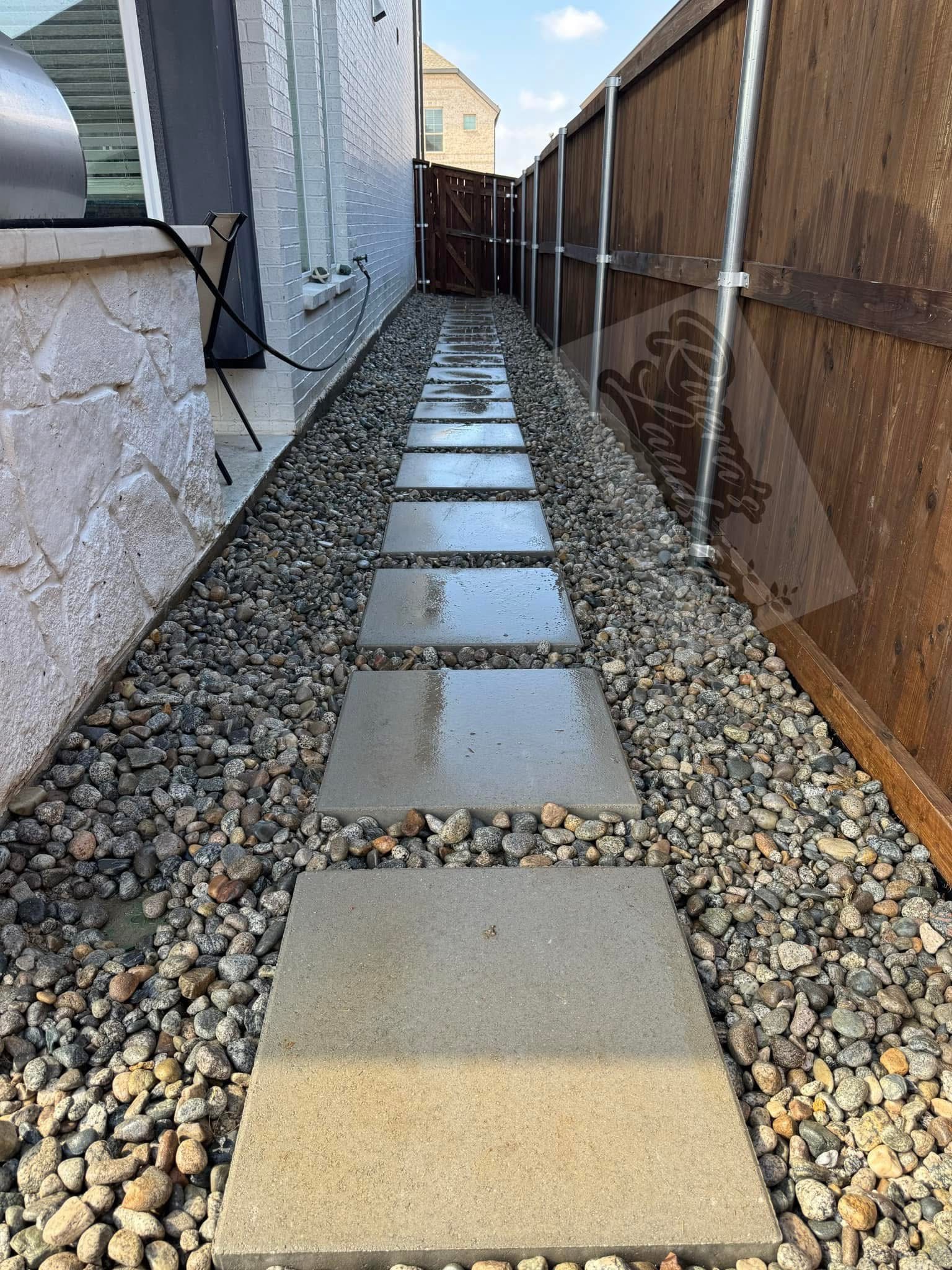 Clean and modern side yard pathway created with large pavers and river gravel for low maintenance.